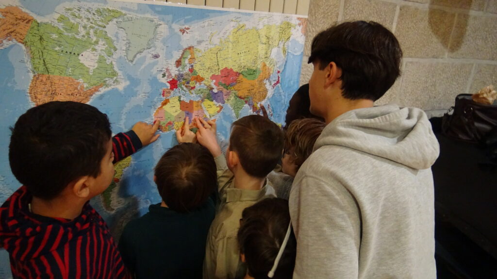 Un groupe de jeunes adolescents pointe une destination sur une mappemonde.